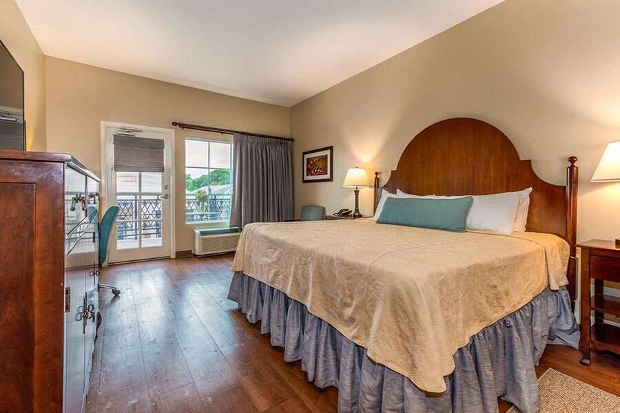 Bedroom with a king-size bed, wooden headboard, and a door leading to a balcony.