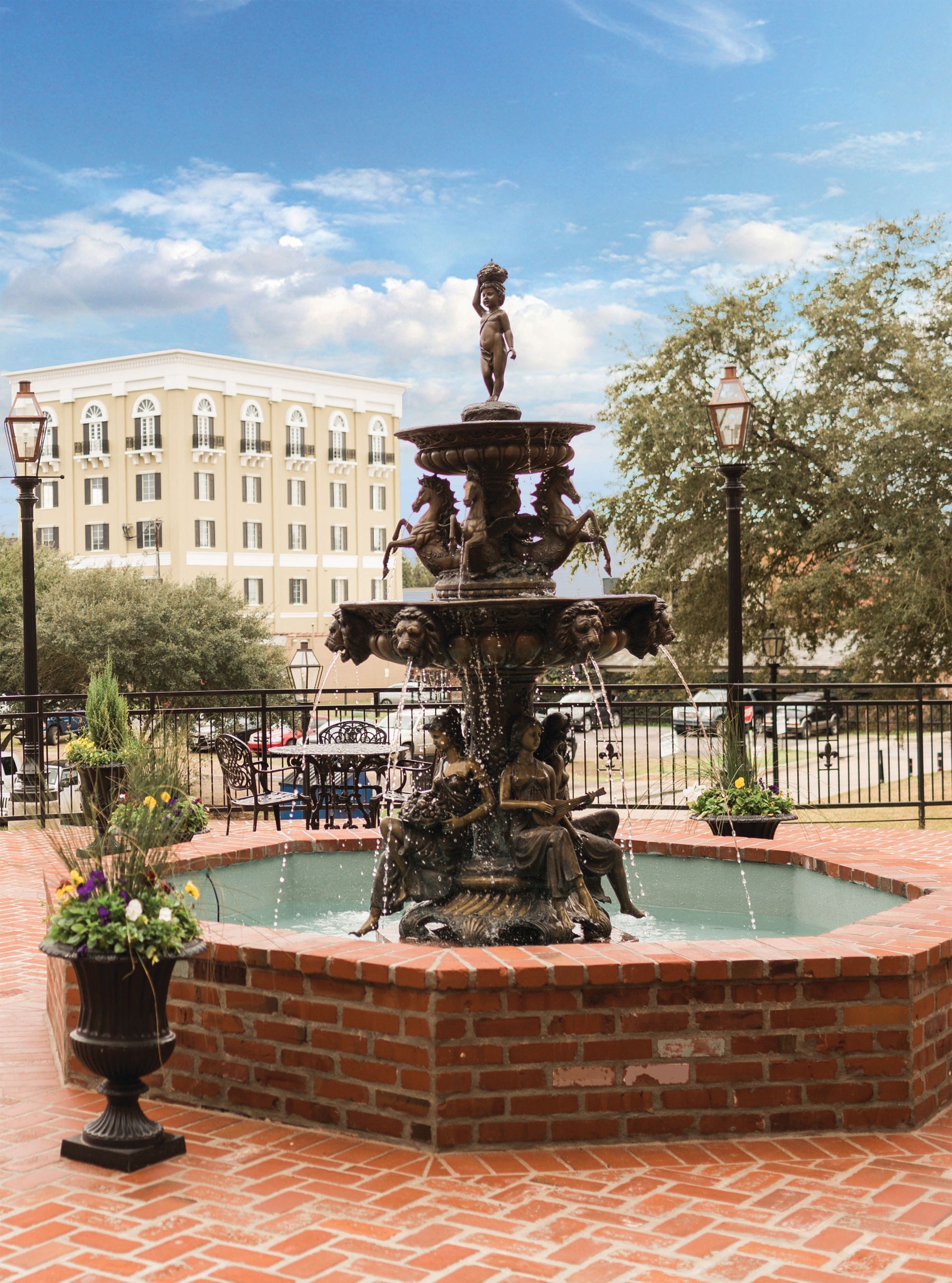 Living room with a sofa, coffee table, dining set, and window with curtains. Beige walls, hardwood floors.