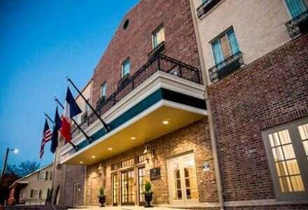 Hotel exterior with flags in front. Brick building with a canopy over the entrance.