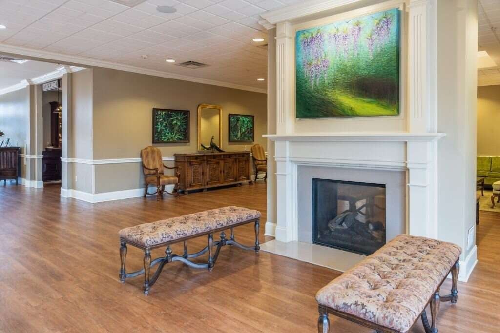 Cozy reception area with fireplace, benches, art, and wood floors.
