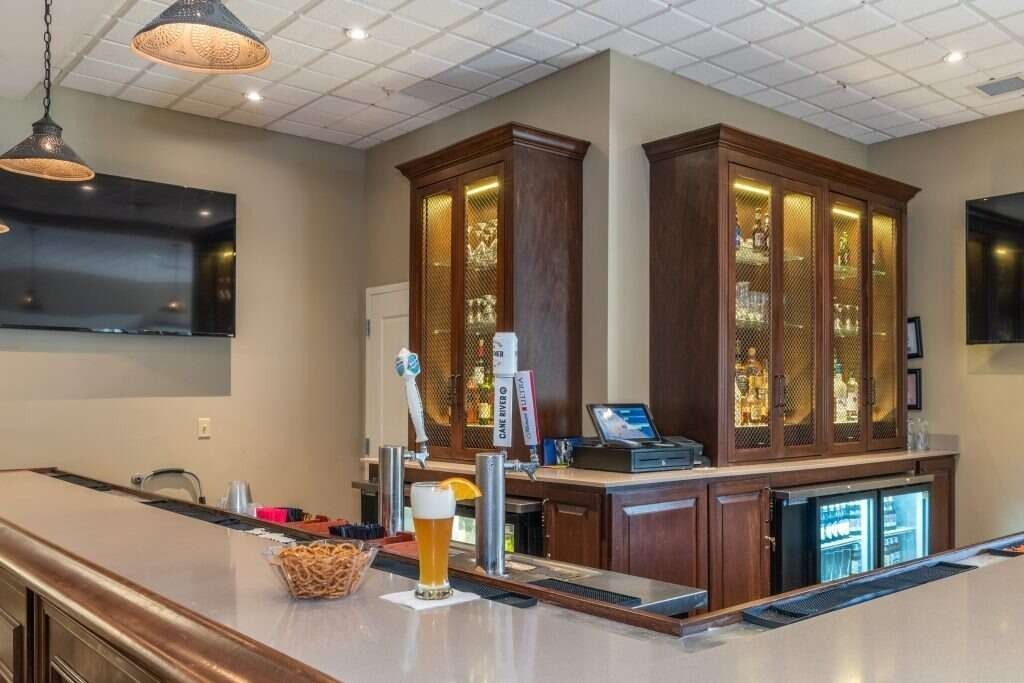 Bar with wooden cabinetry, beer taps, and a glass of beer on the counter.