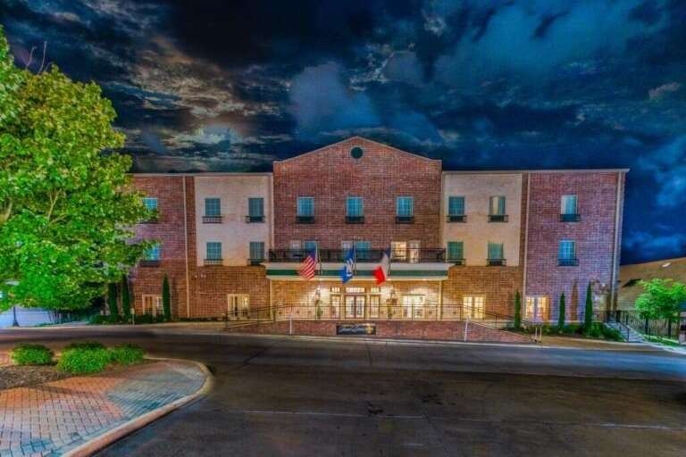 Hotel exterior at night with brick facade, under dark, cloudy sky.