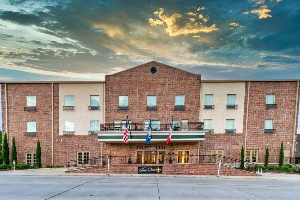 Hotel exterior with brick facade, three flags, and a cloudy sky.
