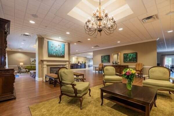 Elegant lobby with green chairs, fireplace, chandelier, and reception desk.
