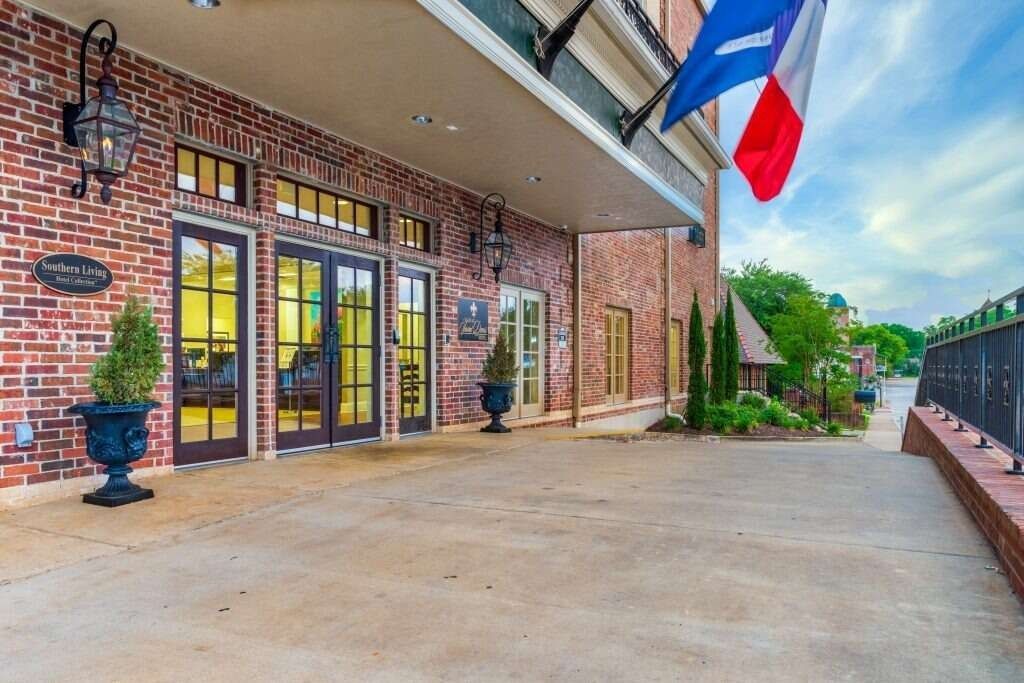 Brick building entrance with French and Texas flags.