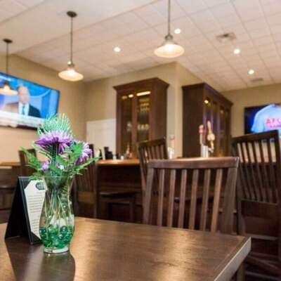 Dining room with wooden tables and chairs, a flower vase, and a TV screen.