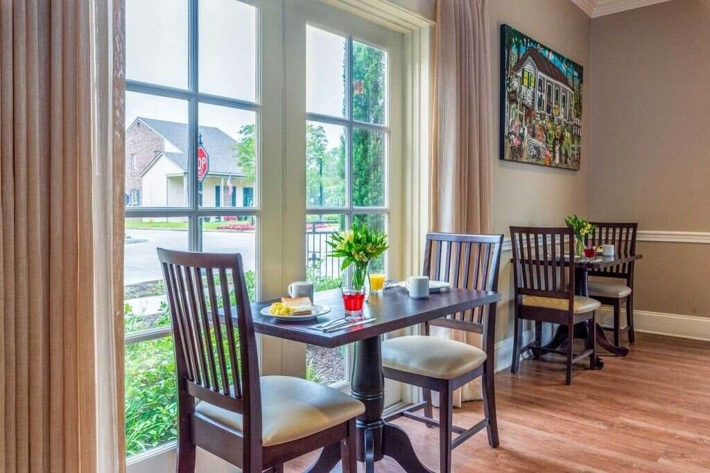 Dining area with small tables set for breakfast near a window overlooking a street.