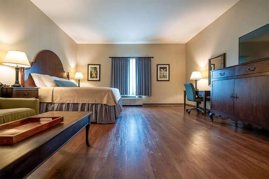 Hotel room with king bed, desk, and hardwood floors.