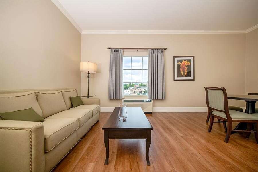 Living room with beige sofa, wooden table, window, and dining table with chairs.