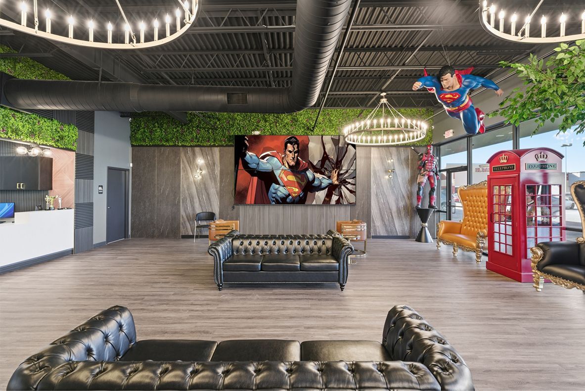 Interior with superhero theme: Superman figure, large screen, leather couches, telephone booth, greenery. Adventure Smiles Dental and Orthodontics -Pasadena