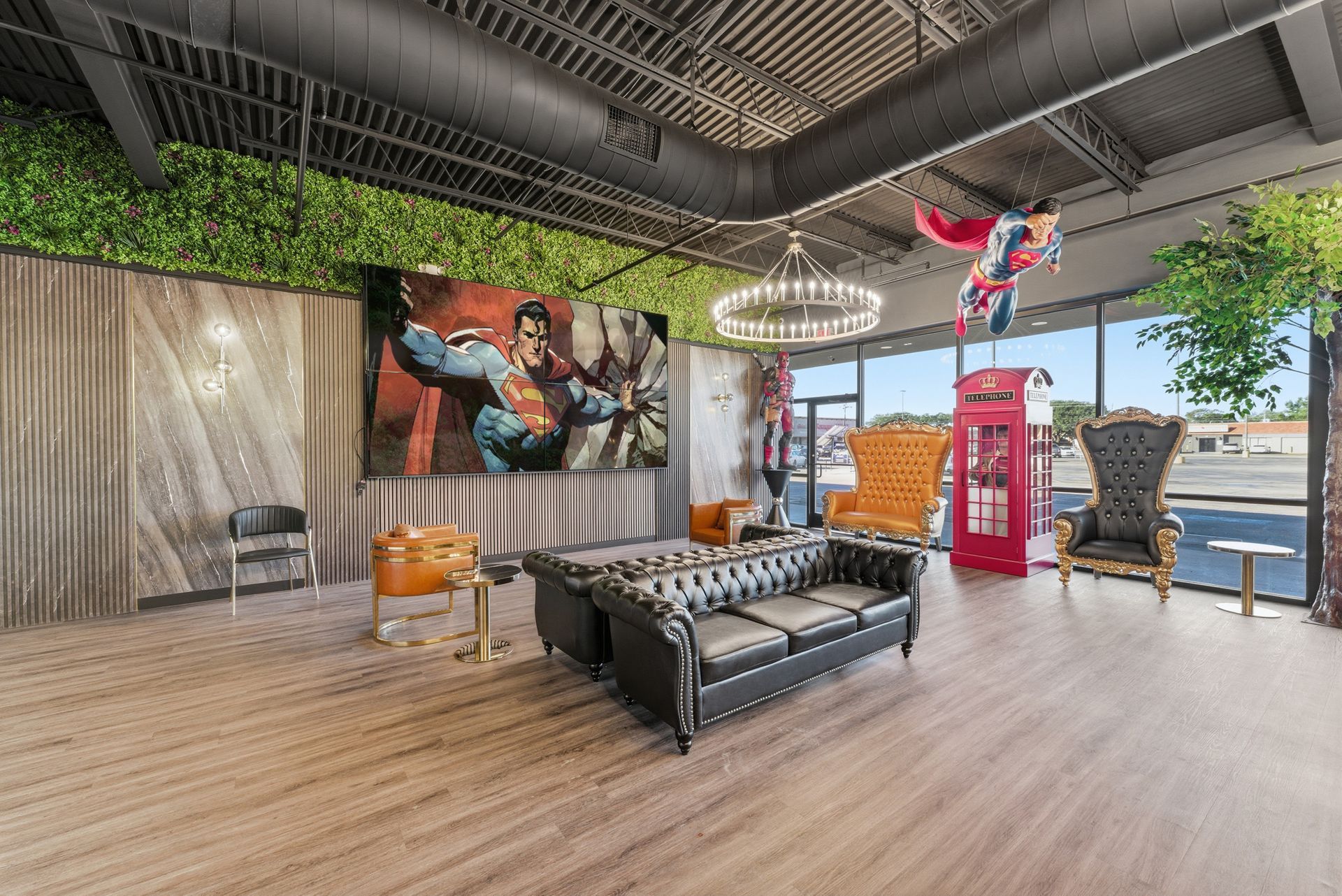 Lounge with superhero theme. Black leather sofa, colorful chairs, large comic art, Superman display, and greenery accent.