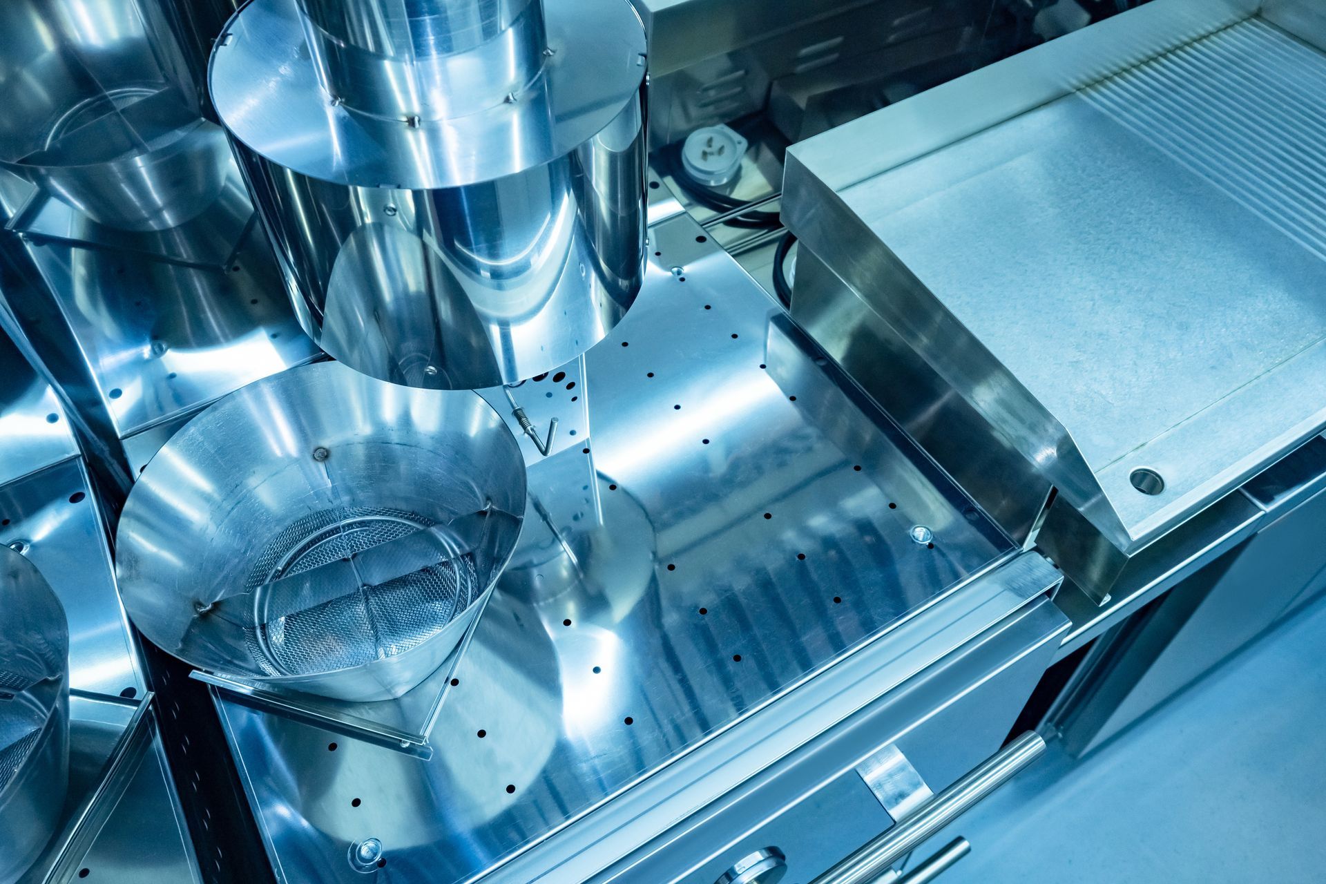 Stainless steel laboratory equipment and glassware on a blue-lit workbench