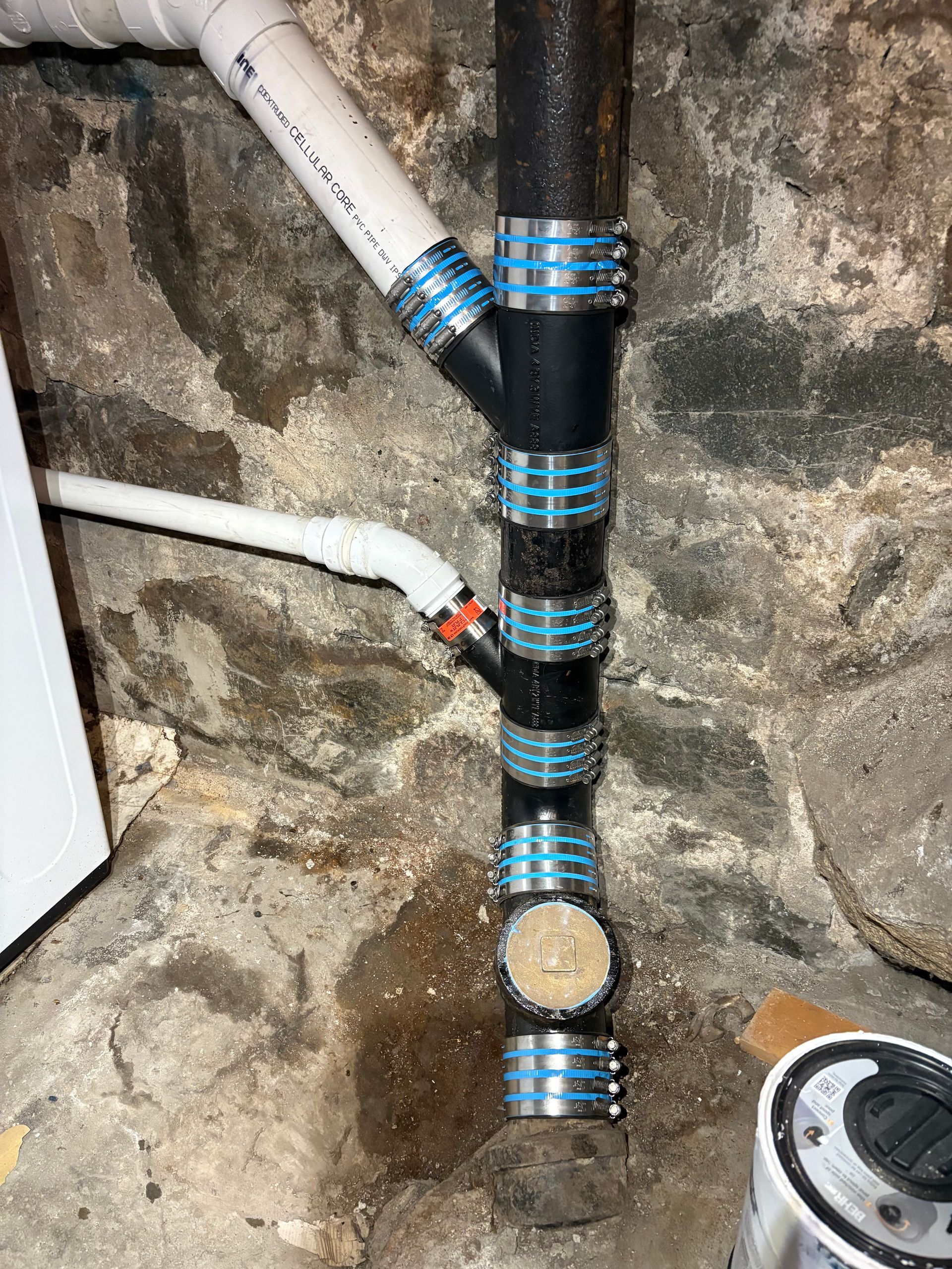 Plumber repairing pipes under a kitchen sink with tools in a white kitchen