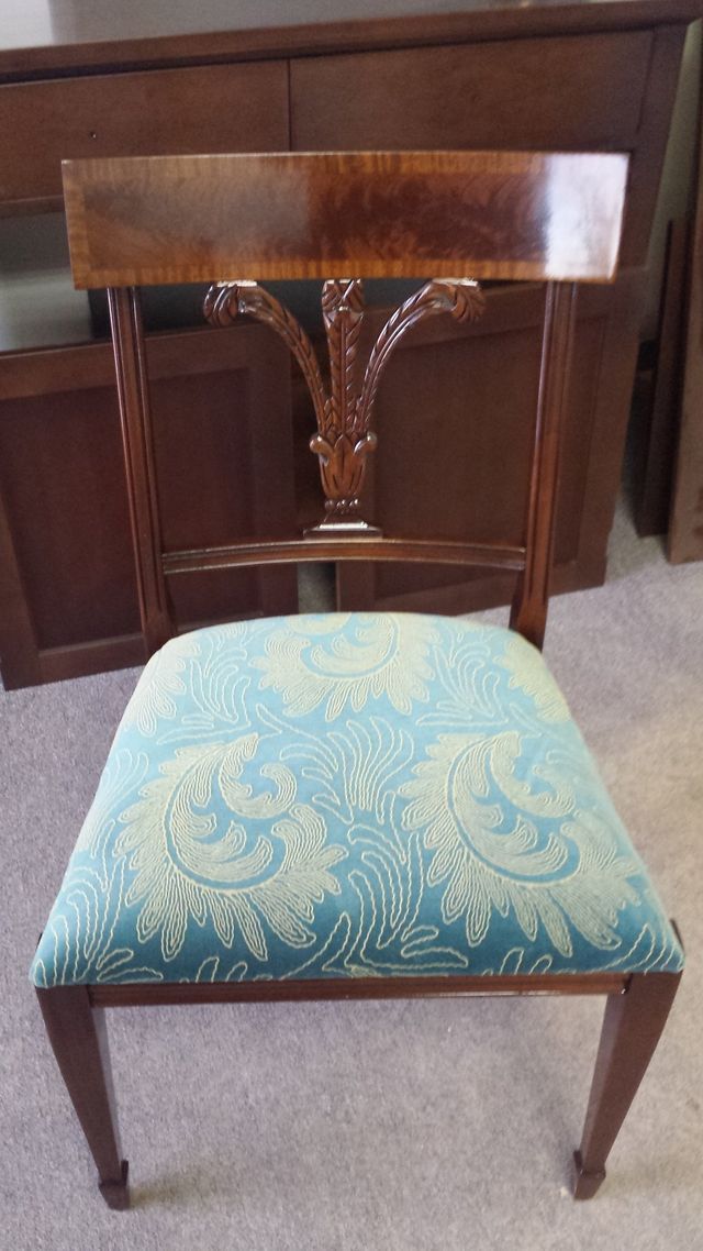 Wooden chair with carved backrest and blue patterned upholstered seat on carpet indoors