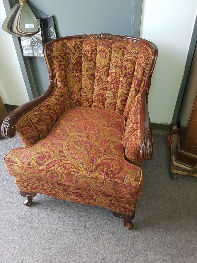 Red patterned upholstered armchair with carved wooden arms in a room