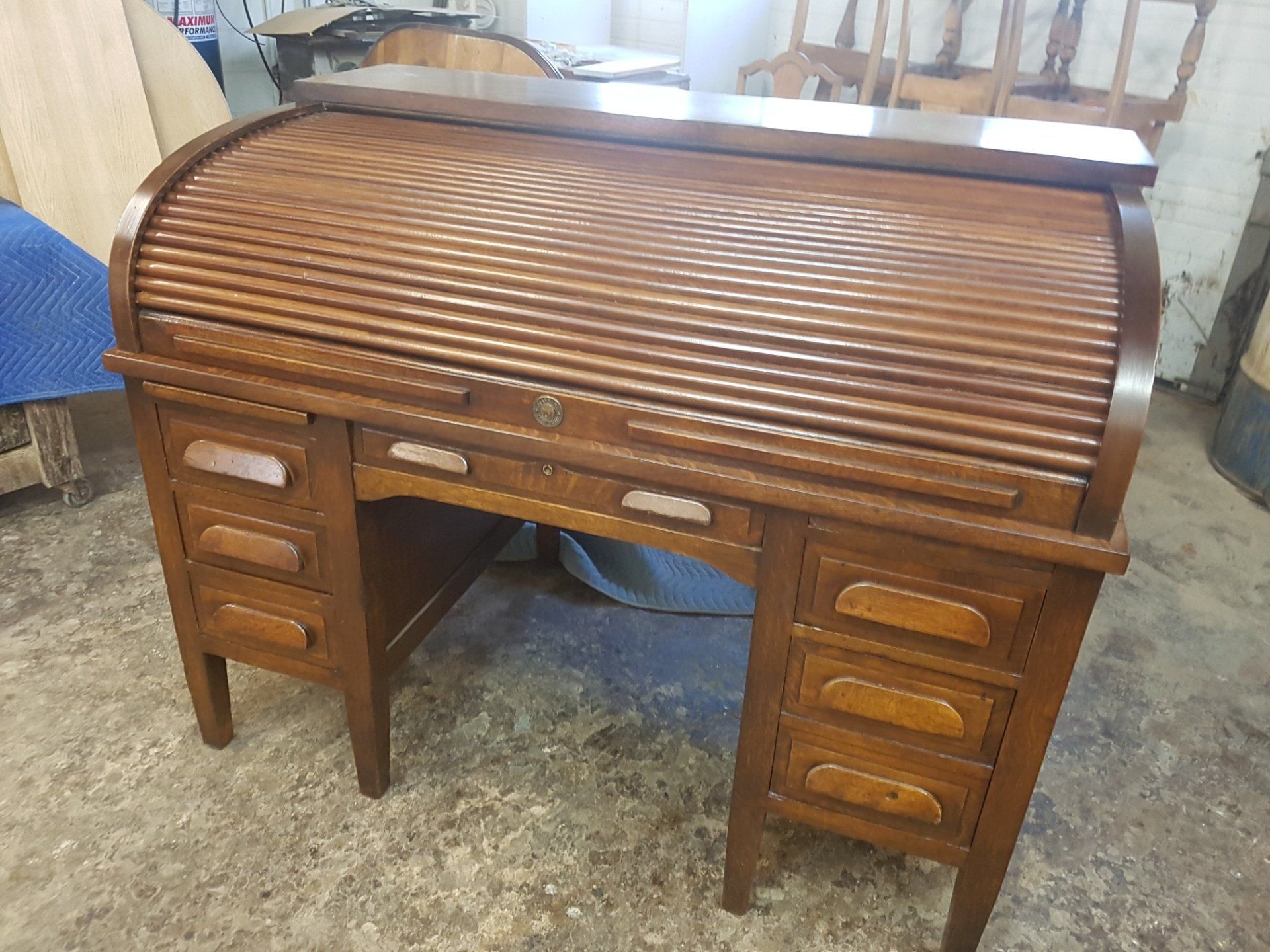 Antique wooden roll-top desk with drawers in a workshop or storage area