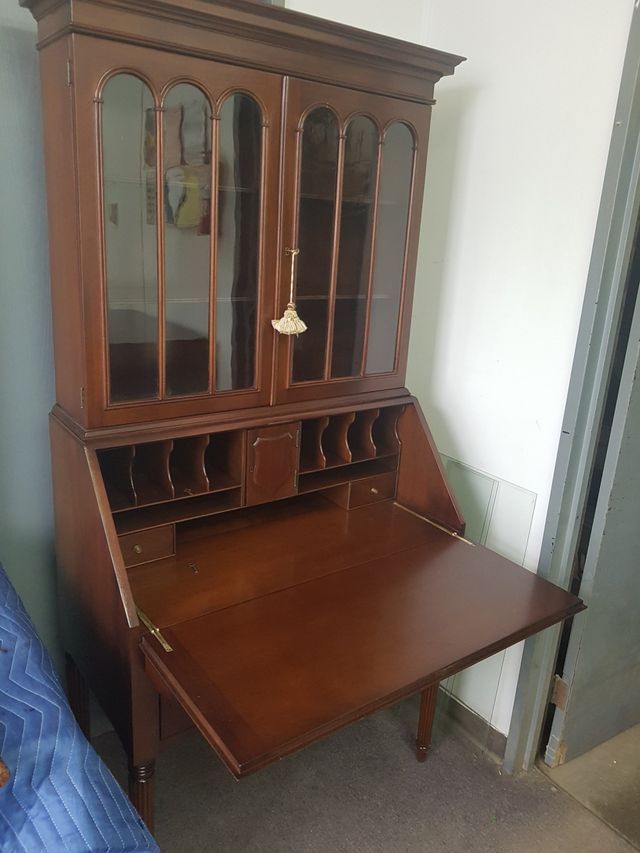 Wooden secretary desk with glass-front cabinet and pull-out writing surface in a small room