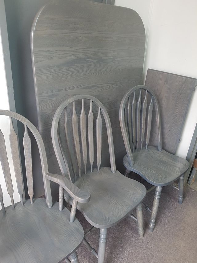Several gray wooden chairs stacked in front of a tall headboard or panel
