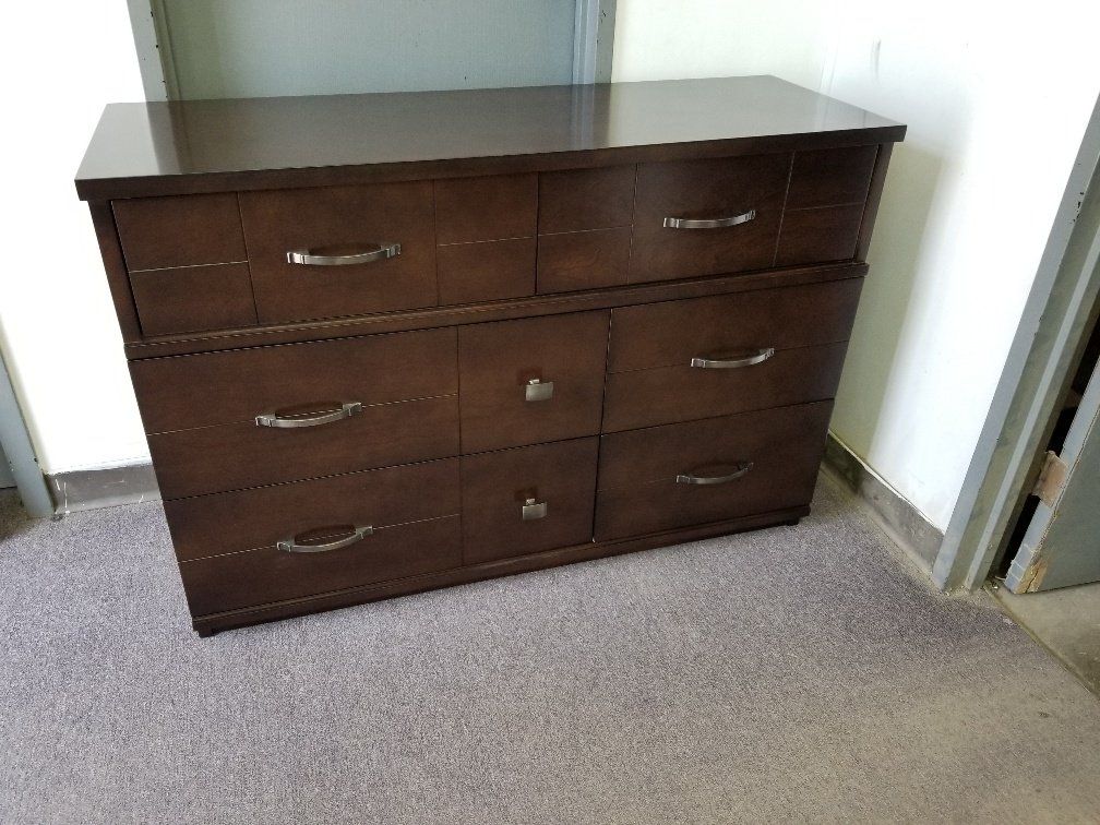 Dark wood dresser with six drawers against a wall in a carpeted room