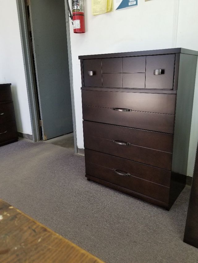 Dark brown dresser with drawers standing against a wall in a room near a doorway.