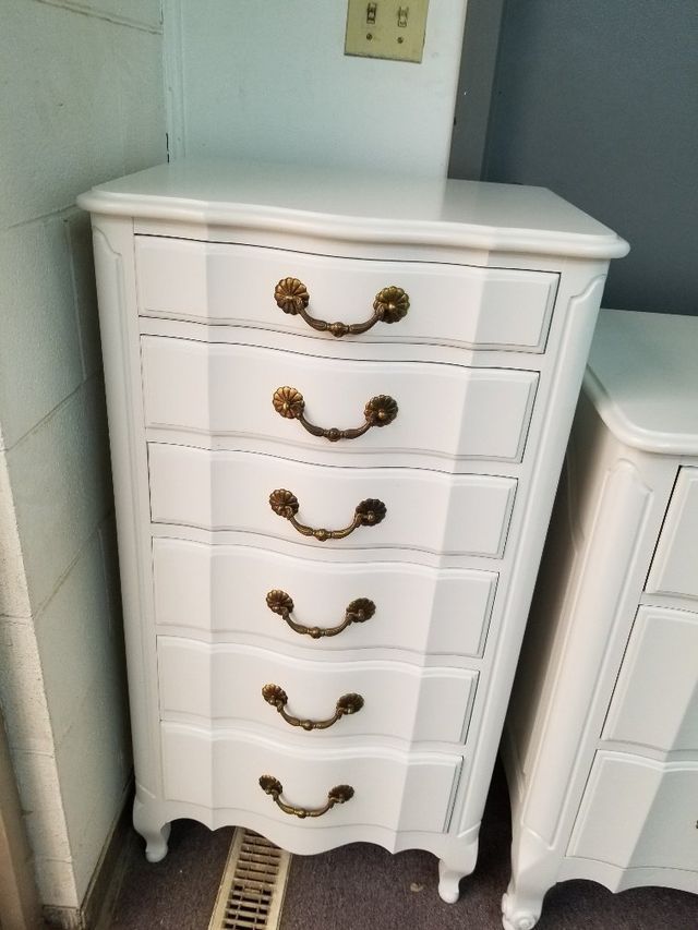 White six-drawer dresser with gold handles against a light wall in a room