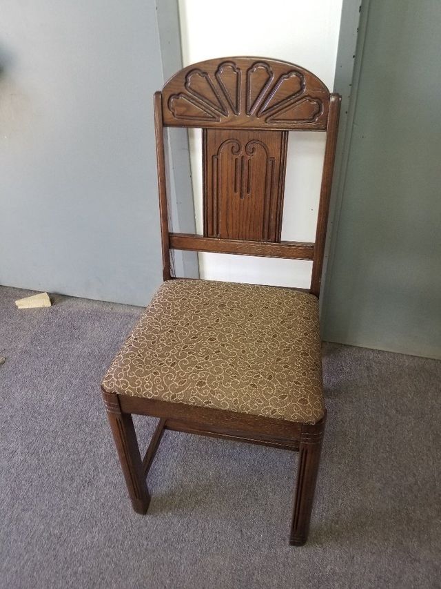 Wooden dining chair with patterned seat cushion against a plain wall