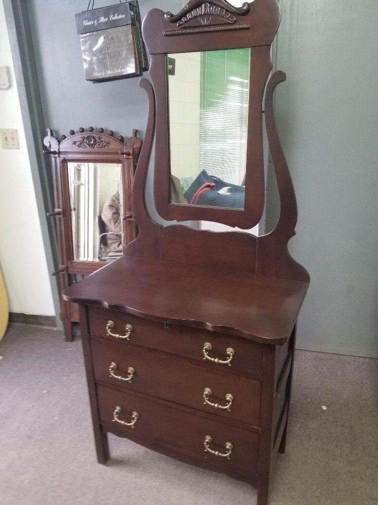 Dark wood vanity with mirror and three drawers in a room, with a smaller matching mirror beside it