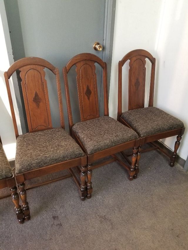 Three wooden dining chairs with upholstered seats lined up against a door.