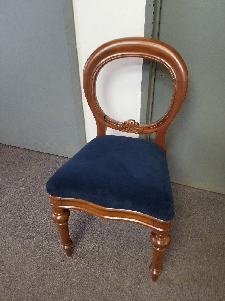 Brown wooden chair with a blue upholstered seat on a carpeted floor
