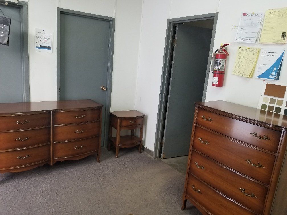 Office hallway with gray doors, wooden dressers, a small table, and wall notices