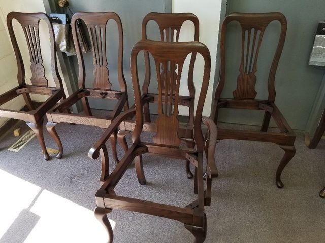 Four wooden chairs with carved backs arranged on a carpeted floor indoors