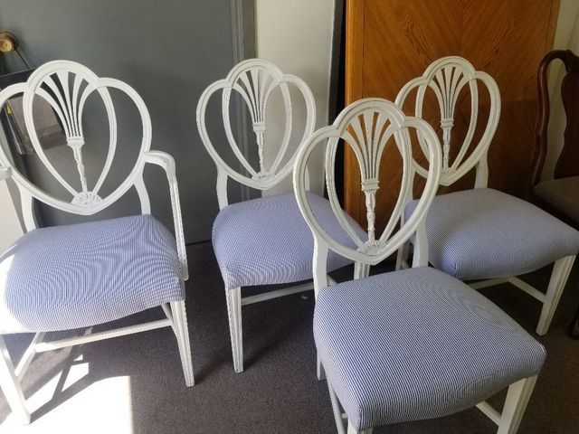 Four white chairs with blue striped cushions arranged in a room near a wooden door.