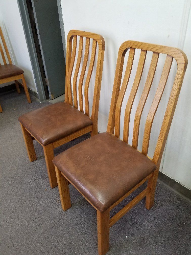 Two wooden chairs with brown cushions against a light wall on a gray carpet