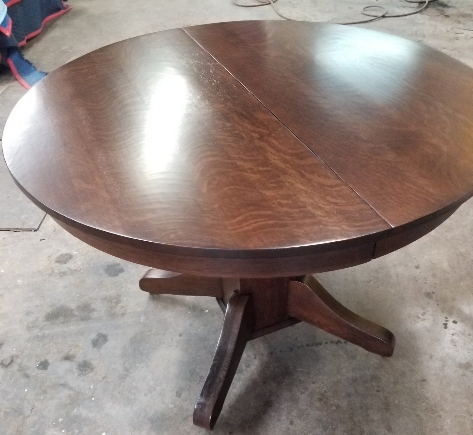 Round dark wood pedestal table in a workshop or garage setting