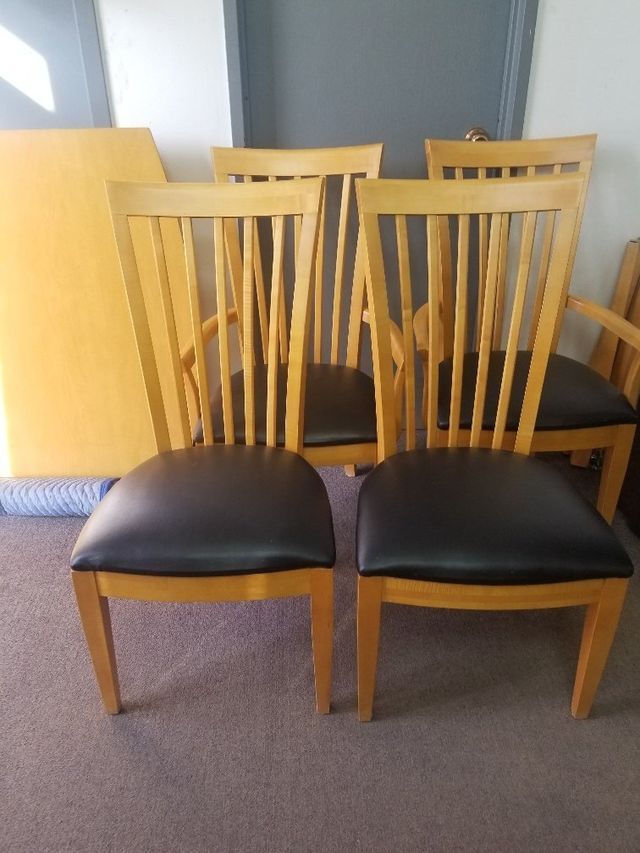 Two wooden chairs with black seats in a carpeted room, with cabinets behind them.