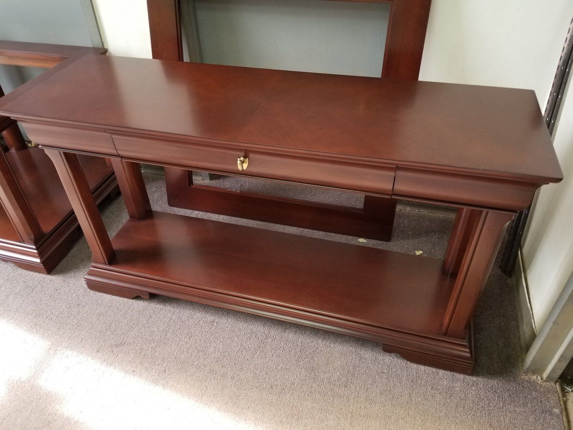Dark wooden TV stand with open shelves and a lower display shelf against a wall.