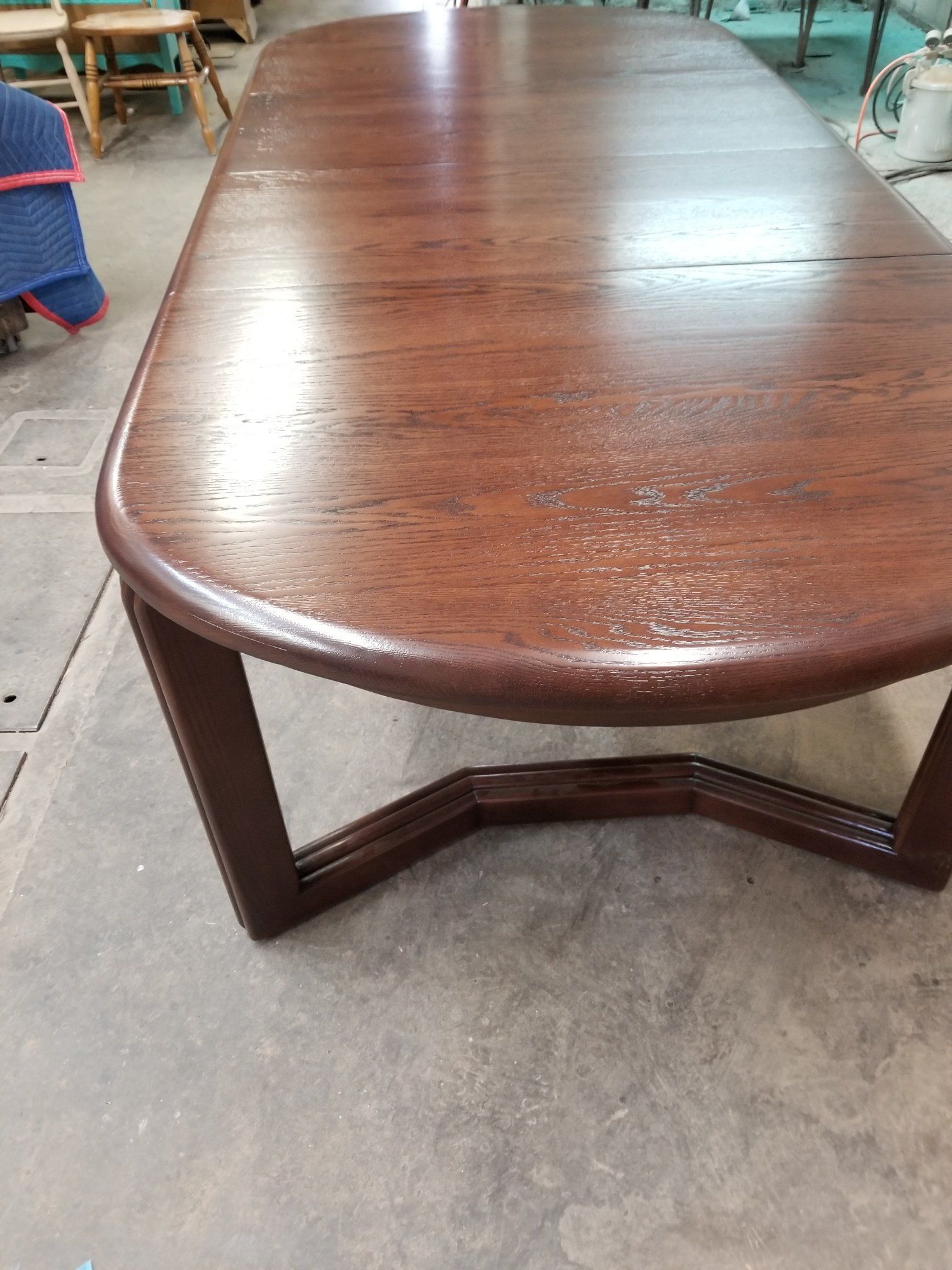 Oval wooden coffee table with curved legs on a concrete floor in a workshop-like space