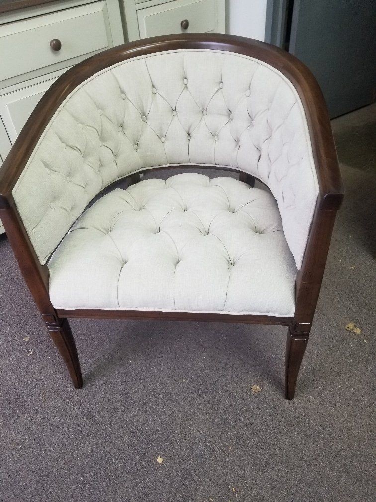 White tufted upholstered armchair with dark wood frame on a carpeted floor.