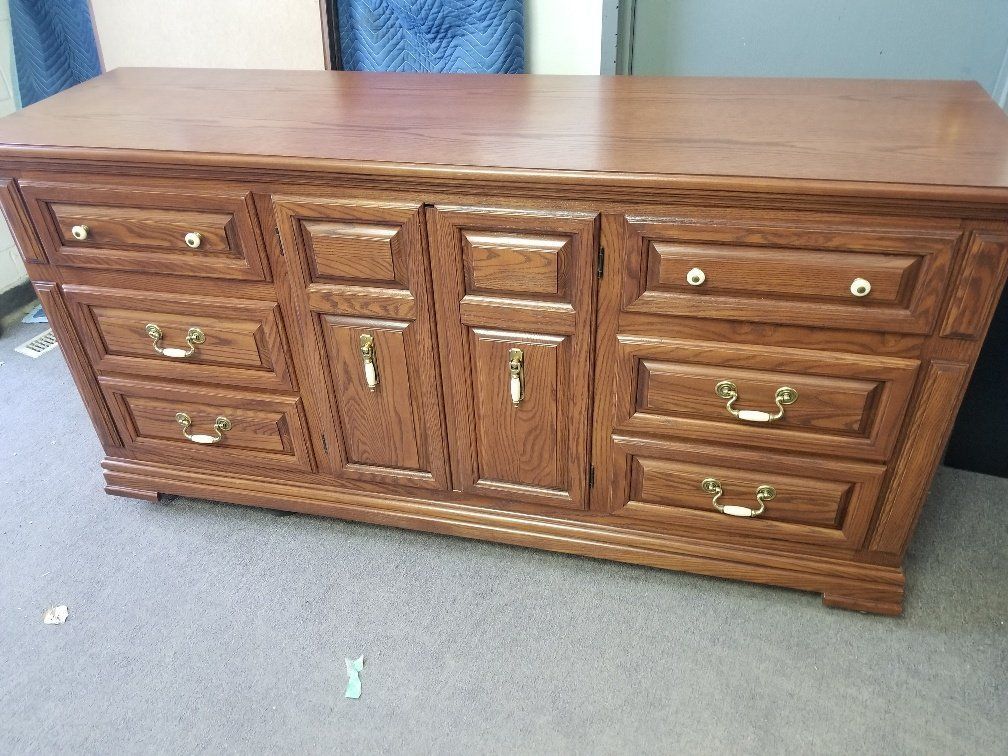 Wooden six-drawer dresser with central cabinet doors on a carpeted floor