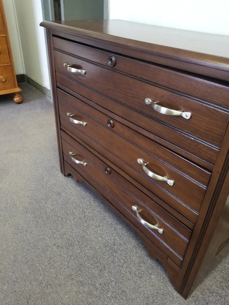 Dark wood dresser with silver handles on a carpeted floor in a room
