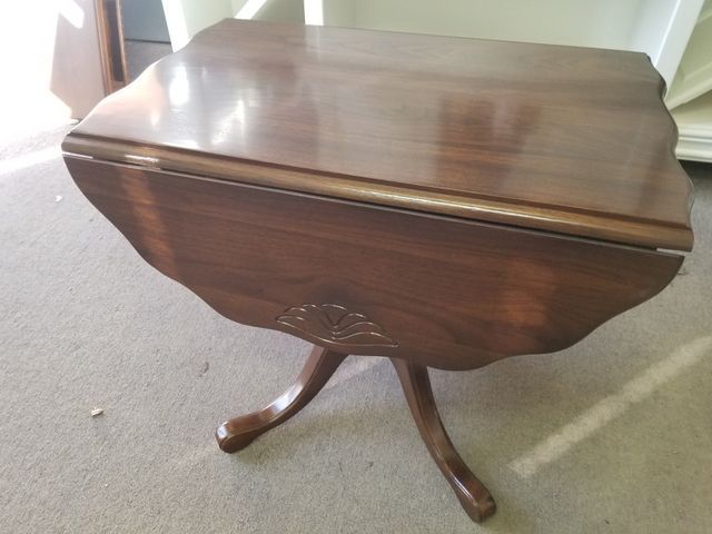 Small wooden drop-leaf table with curved legs on a carpeted floor