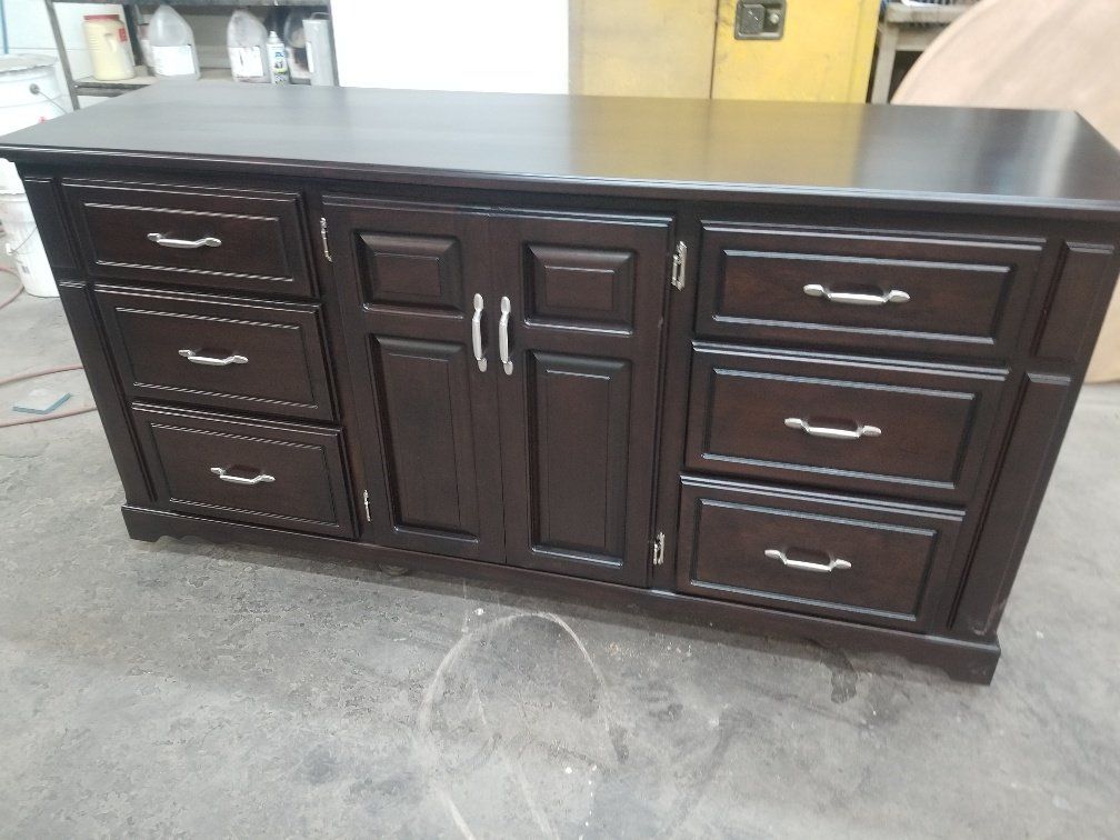 Dark wood kitchen island with black countertop and multiple drawers and cabinet doors