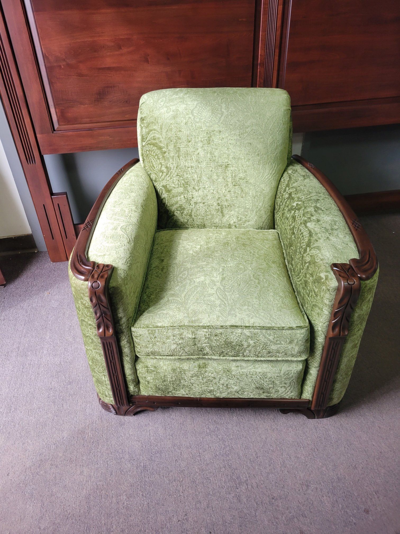 Green upholstered armchair beside a wooden cabinet on a carpeted floor