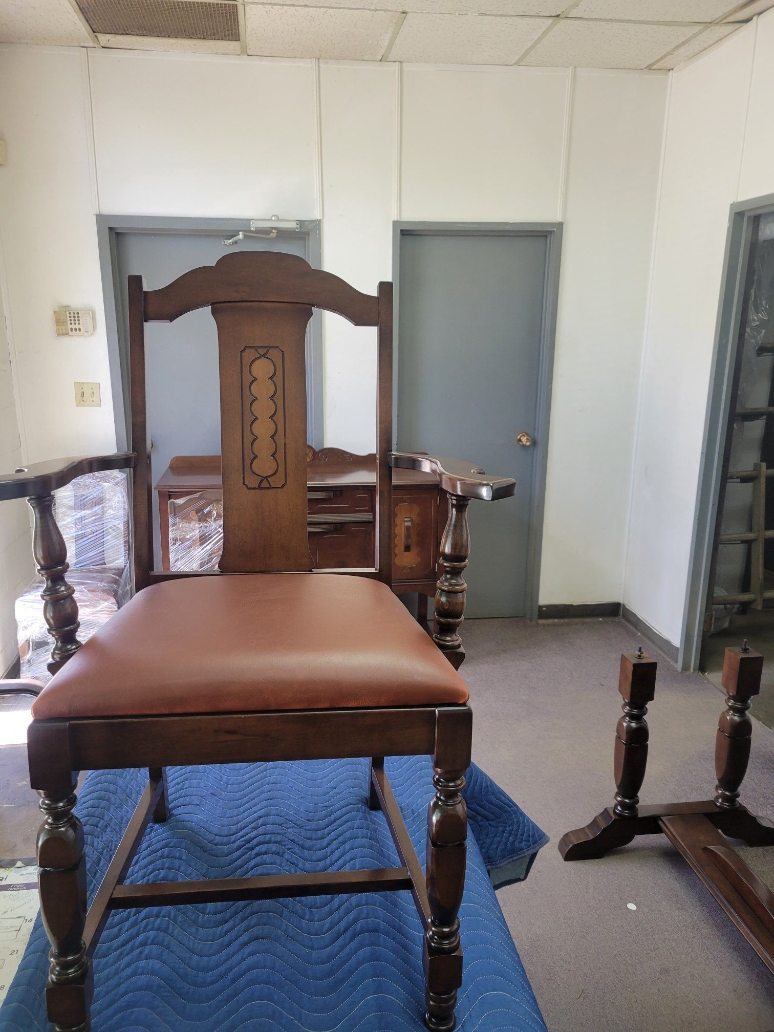 Wooden upholstered chair in a small room with white walls and a desk in the background
