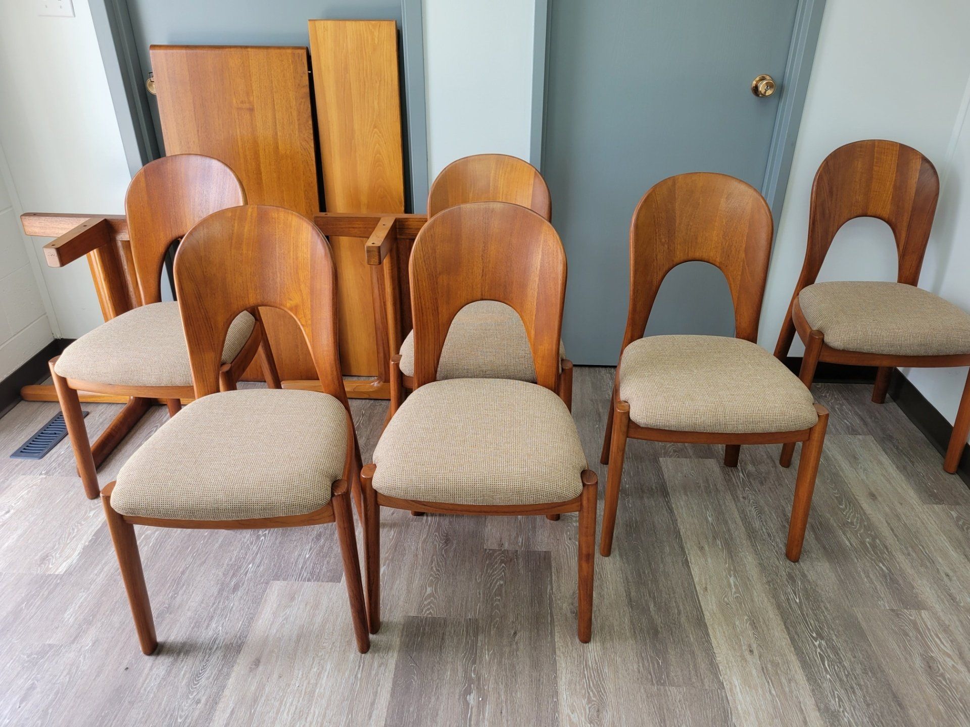 Rows of wooden chairs with beige cushions in a room with blue walls and cabinets.