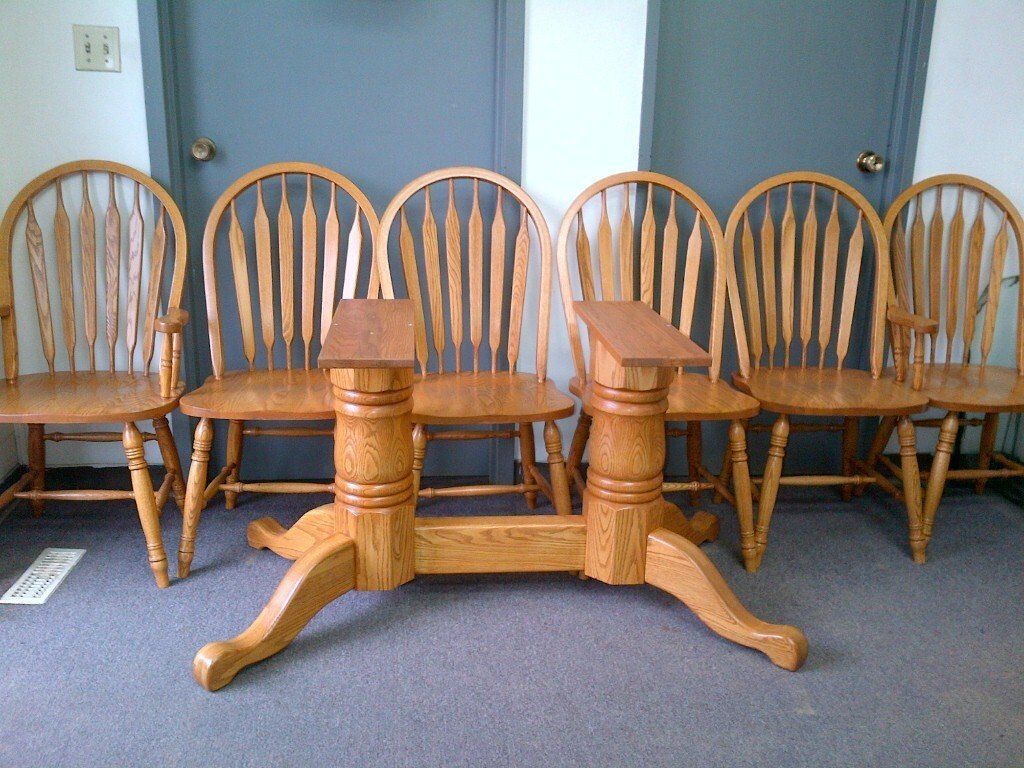Wooden dining table with five matching chairs on a blue carpet against a gray wall.