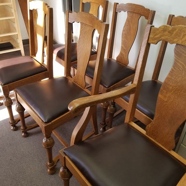 Row of wooden dining chairs with dark cushions in a sunlit room