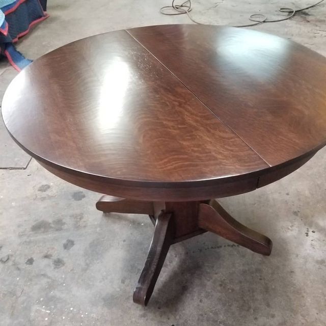 Round dark wood dining table with pedestal base in a workshop setting