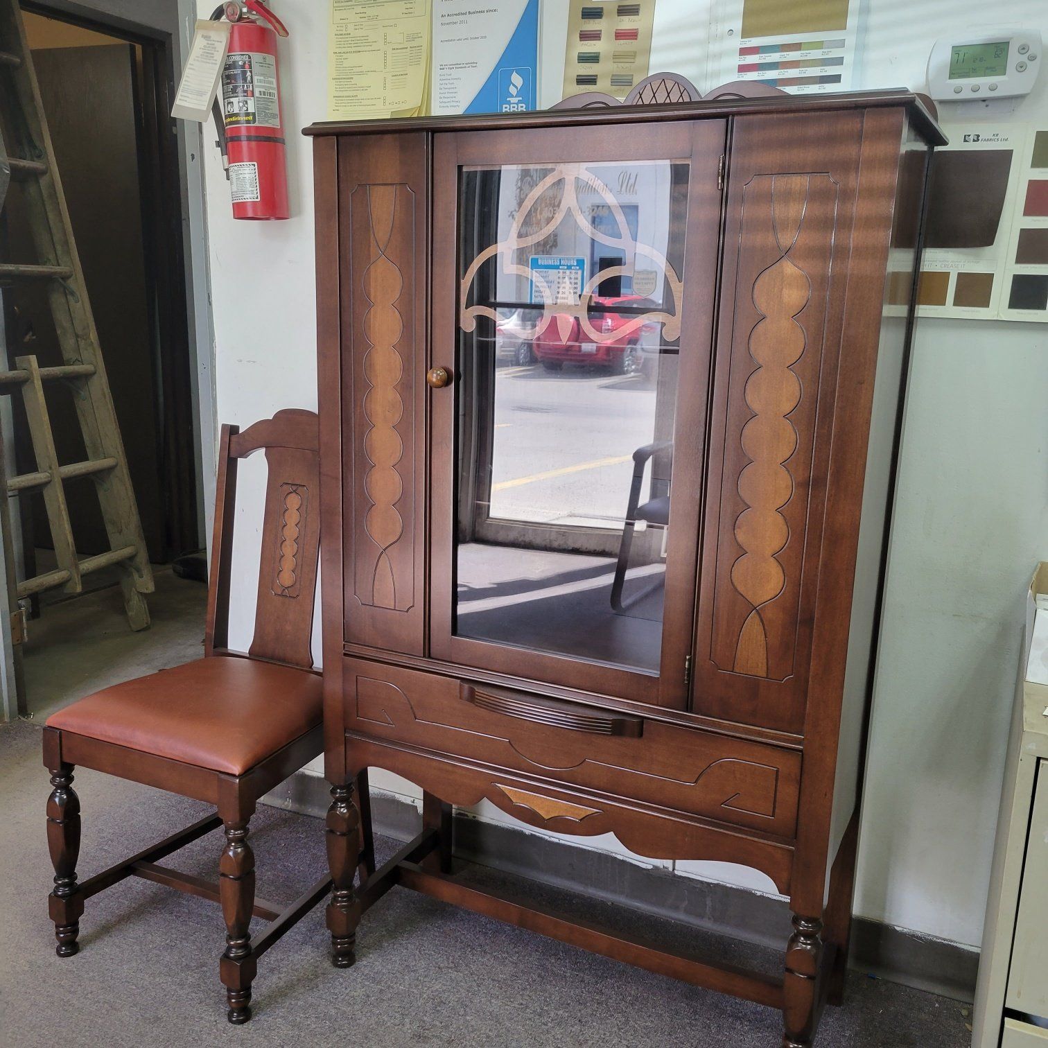 Wooden wardrobe with mirrored door beside a brown upholstered chair in a room