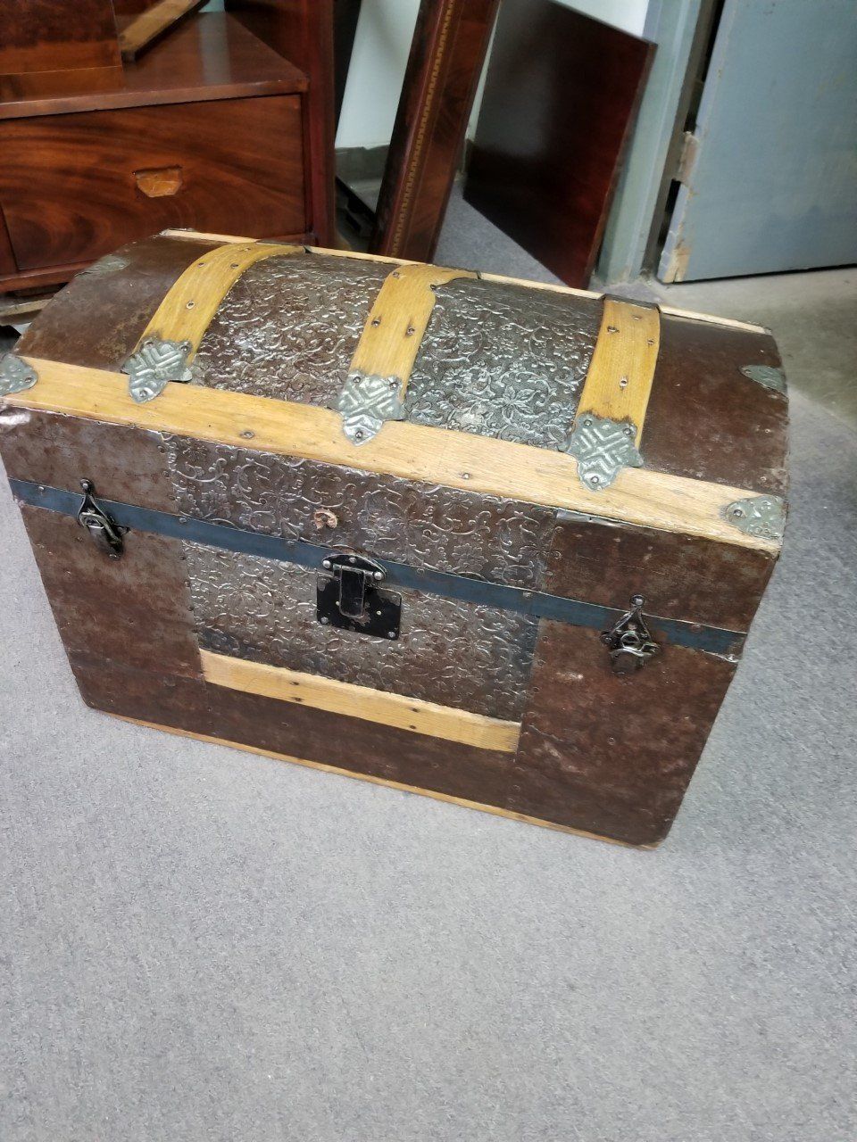 Old wooden treasure chest with brass bands and a curved lid on a carpeted floor